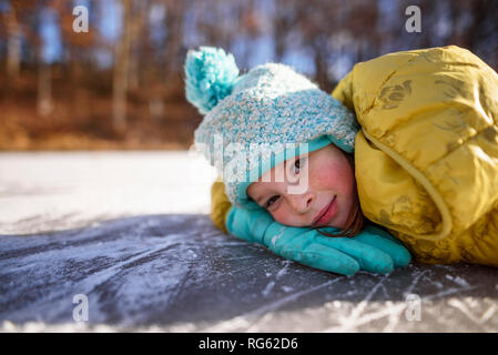 Portrait of a smiling girl lying on a frozen pond, United States Stock Photo