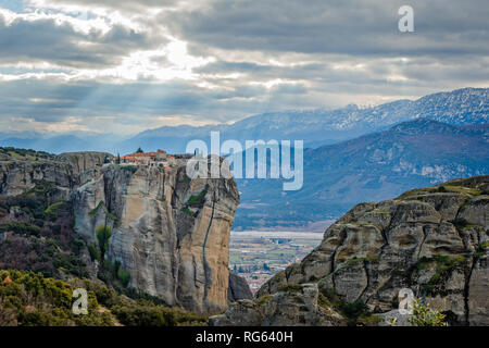 Agios Stephanos or Saint Stephen monastery situated on the huge rock with sunset rays and mountains in the background, Meteors, Trikala, Thessaly, Gre Stock Photo