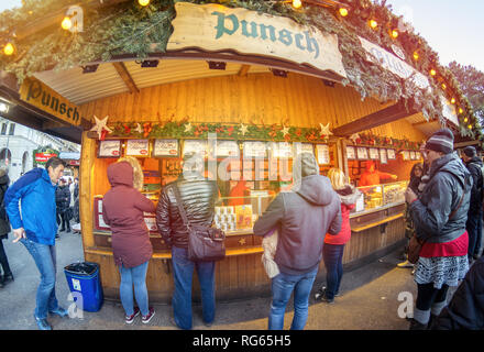 Vienna Austria December 26 ,2018: Visitors to Vienna Christkindlmarkt Christmas Market stand in front of a stand selling gingerbread and punch. Stock Photo