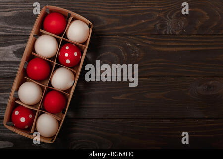 Happy Easter! Painted Easter eggs - red, white and red with white polka dots on a brown wooden background. Selective focus. Stock Photo