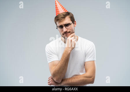 Picture of unhappy stressed young man having unhappy look, feeling tired and worn out with birthday party preparations, standing in studio. Stock Photo