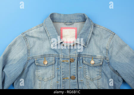 Clothes, shoes and accessories - top view fragment blue jeans jacket empty label on a blue background Stock Photo