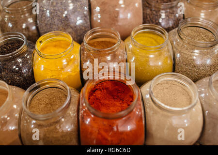 Zero waste shopping - spices in jars. Composition of colorful assorted spices and herbs in glass jars in packaging free shop. Stock Photo