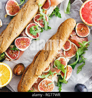 Sandwich with prosciutto, mascarpone cheese and figs on wooden table top view Stock Photo