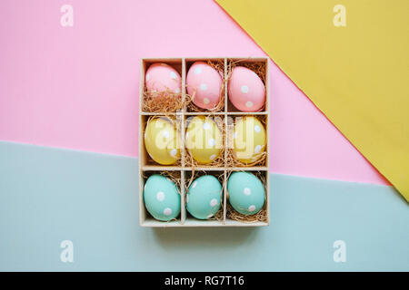 Gift or holiday box or container with colorful Easter eggs on a bright multi-colored background. Easter celebration concept in minimal style. Stock Photo