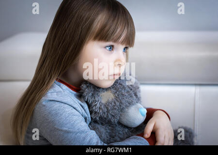 Portrait of little girl. Kid sad face sitting alone in the room. Stock Photo