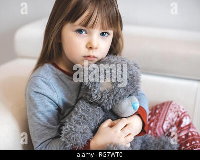 Portrait of little girl. Kid sad face sitting alone in the room. Stock Photo