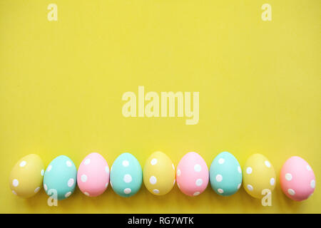Set of multicolored easter eggs in a row on a yellow background. Festive Easter concept in minimal style. Above there is a place for text. Stock Photo