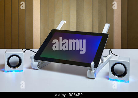 Tablet PC is connected to small external speakers. Stock Photo