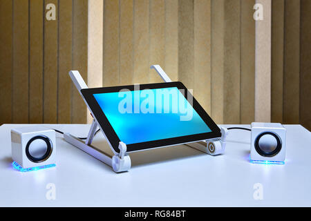 Tablet computer is connected to portable external speakers. Stock Photo