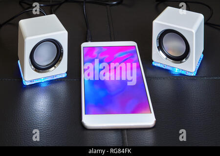USB led speakers are connected to a smartphone with a bright display screen. Stock Photo