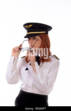 Young female pilot with red hair standing in airline uniform including a hat Stock Photo