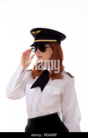 Young female pilot with red hair standing in airline uniform including a hat Stock Photo