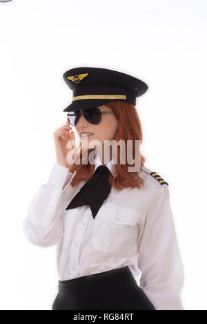 Young female pilot with red hair standing in airline uniform including a hat Stock Photo