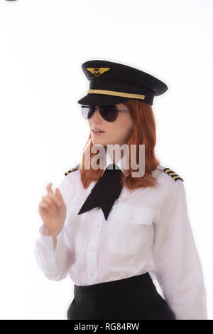 Young female pilot with red hair standing in airline uniform including a hat Stock Photo