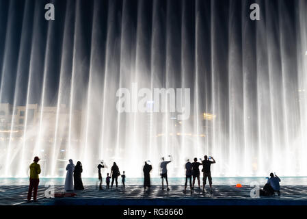 Silhouettes of people enjoying the fountain show in Dubai at night, United Arab Emirates Stock Photo