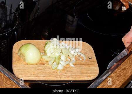 Chef slicing Onion, Allium cepa on the cutting board with a knife. Stock Photo