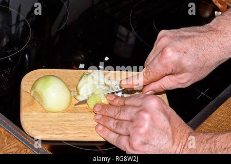 Chef slicing Onion, Allium cepa on the cutting board with a knife. Stock Photo