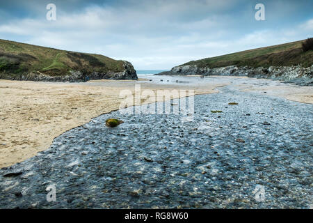 A small river flowing over the beach at low tide in Polly Porth Joke in Newquay in Cornwall. Stock Photo