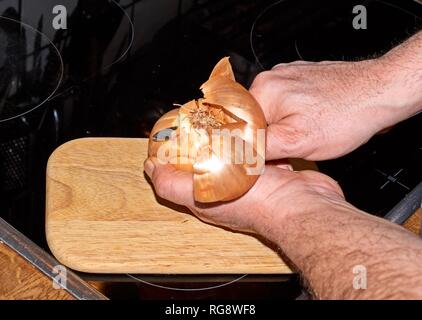 Chef slicing Onion, Allium cepa on the cutting board with a knife Stock Photo