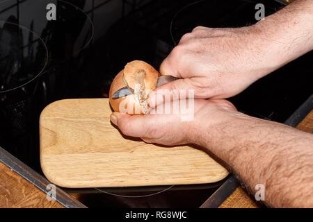 Chef slicing Onion, Allium cepa on the cutting board with a knife Stock Photo