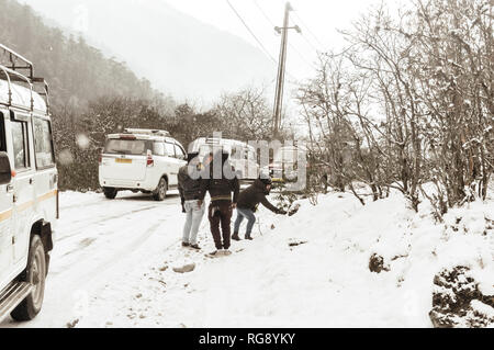 Yumthang Valley, Sikkim, India 1st January 2019: Group of Tourist in winter clothes enjoying snow at snowfall on a day with heavy snow hill slope near Stock Photo