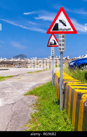 Caution Chinese road sign mounted on ocean coast in Taiwan. Text label means: Drive carefully, pier embankment Stock Photo