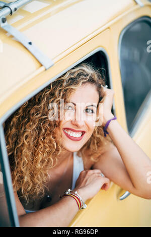 Portrait of happy blond woman looking out of window of classic car Stock Photo