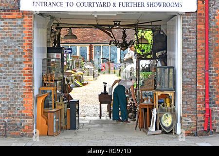 Woman arranging display of antiques  collectables & bric a brac in entrance to dealer courtyard & showroom shop at Hungerford Berkshire England UK Stock Photo