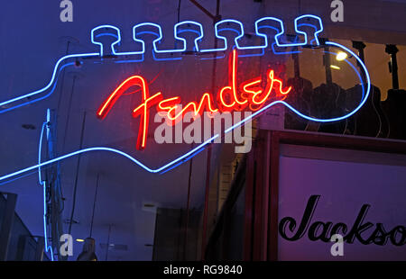 Neon Fender guitar logo glowing in a specialist musical instrument shop, combining iconic electric-guitar branding with traditional music retail. Stock Photo