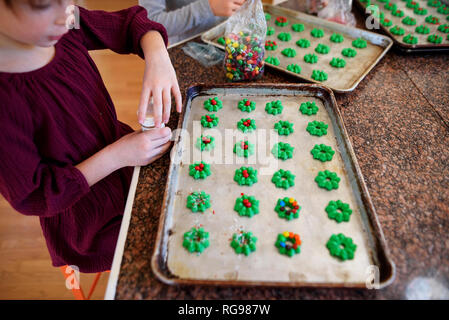 Two children standing in the kitchen decorating cookies Stock Photo