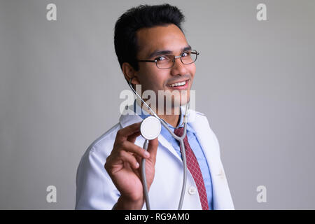 Portrait of happy young Indian man doctor using stethoscope Stock Photo