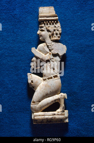 Kneeling male figure: Nimrud Ivory from Room SW37 Fort Shalmaneser within the Assyrian city of Nimrud, Iraq, photographed in the Iraq Museum, Baghdad. Stock Photo