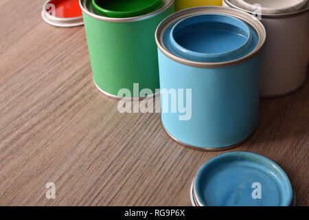 Assortment open paint cans and their covers on wooden table. elevated view. Horizontal composition. Stock Photo