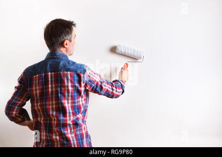 Man painting a white wall in his house. Diy home concept. Front view. Horizontal composition. Stock Photo