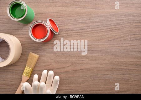 Two cans of paint, brush,gloves and masking tape on wooden table. Top view. Horizontal composition. Stock Photo