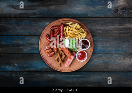 Beer snacks set. Grilled sausages and french fries served with tomato and BBQ sauce. Stock Photo