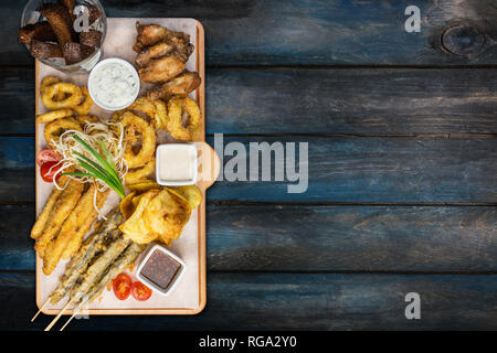 Beer snacks set. Fish set served on cutting board with the mugs, on the wooden background. Stock Photo