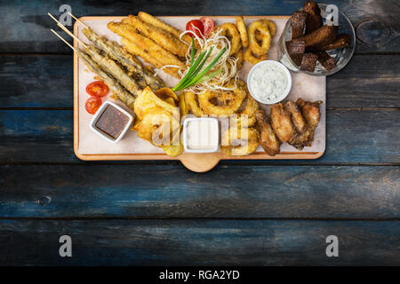 Beer snacks set. Fish set served on cutting board with the mugs, on the wooden background. Stock Photo