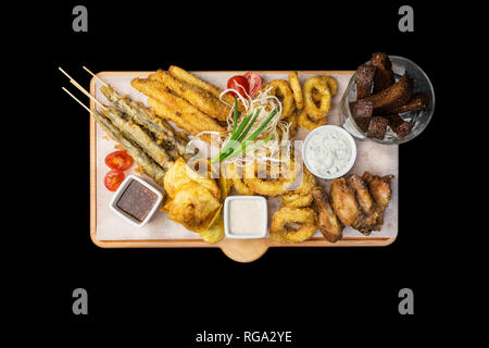 Beer snacks set. Fish set served on cutting board with the mugs, isolated on the black background. Stock Photo