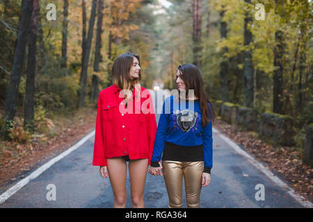 Two young women standing on country road facing each other Stock Photo