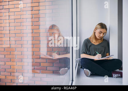 Student sitting at the window in hallway learning Stock Photo