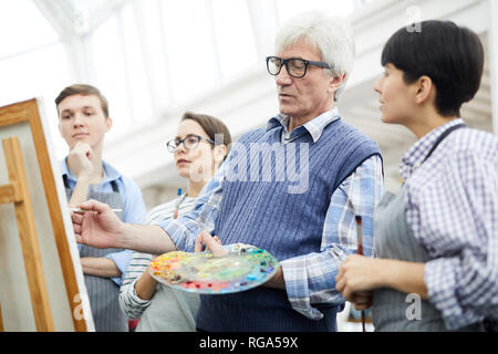 Waist up portrait of mature art teacher working with group of students in art class, copy space Stock Photo