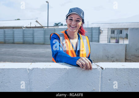 Portrait of smiling young woman wearing overalls and reflective jacket Stock Photo