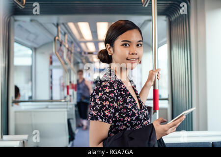 Smiling Asian student commuting to work on a train Stock Photo