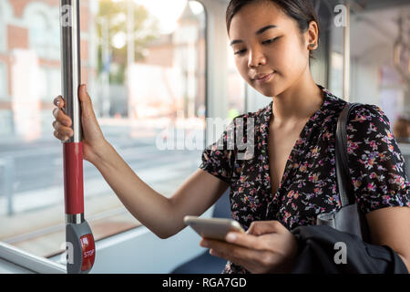 Young Asian businesswoman riding on a city train reading texts Stock Photo