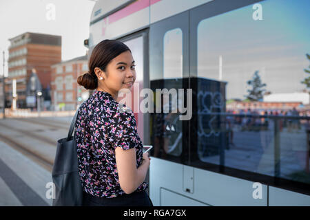 Portrait of a smiling young Asian businesswoman about to board a bus while commuting to work in the city Stock Photo