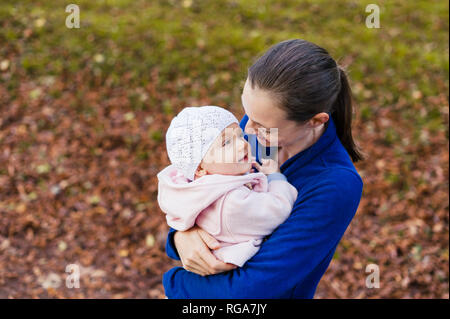 Mother hugging daughter in autumnal park Stock Photo