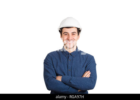 Cheerful confident young man engineer arms crossed wearing protective helmet smiling looking to camera isolated over white background. Stock Photo