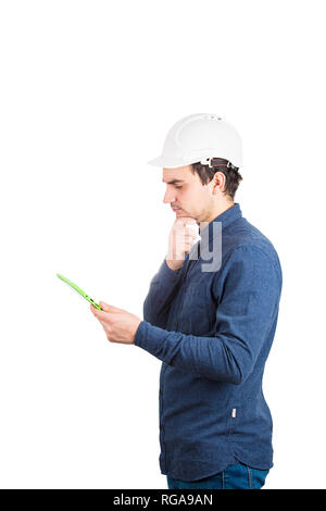 Side view thoughtful of young man engineer wearing protective helmet using a tablet computer gadget to calculate isolated over white background. Stock Photo